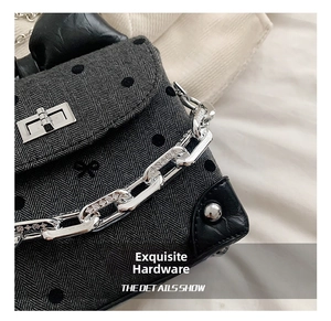 Close-up of silver hardware clasp and chain on a polka dot and herringbone bag