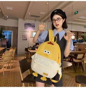 Detail of yellow cartoon chicken backpack with 3D feet and wings in a cafe setting