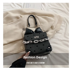 Detailed shot of dark grey polka dot bag featuring a large leather bow and chain strap