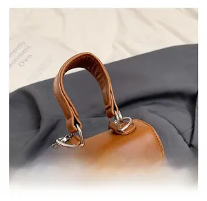 Detail showing brown leather texture and silver twist lock on the kids handbag