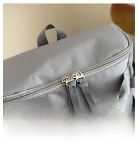 Detail of smooth metal double-way zipper on textured nylon grey sports backpack