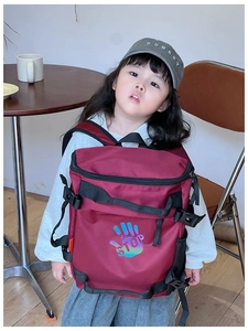 Kid wearing a burgundy backpack with a colorful palm print and mesh side pocket