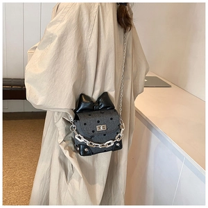 Detailed side view of polka dot crossbody bag with leather bow and silver chain on model