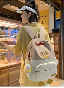 Close-up of cute cartoon chicken backpack with funny embroidery and plush sunflower charm