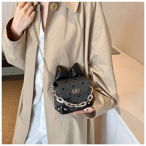 Close-up of grey polka dot crossbody bag with a large black bow and silver chain strap