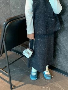 Dettaglio del set in tweed grigio per bambina con borsa a tracolla con fiocco bianco