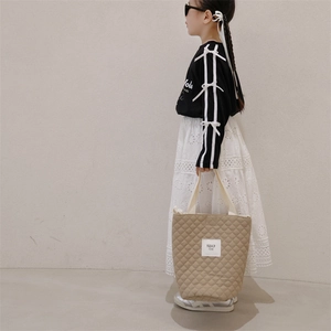 Gesteppte beige Tragetasche für Mädchen mit Rautenmuster und gewebten Griffen am Model