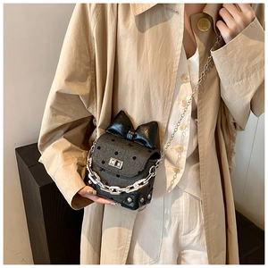 Detail of mini polka dot crossbody bag with large black bow and silver chunky metal chain