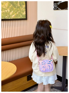 Close-up of a child wearing a purple sequined butterfly crossbody bag with pink straps