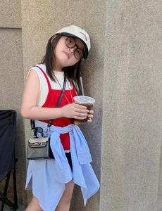 Detail of red sleeveless vest and white top with a black mini crossbody bag