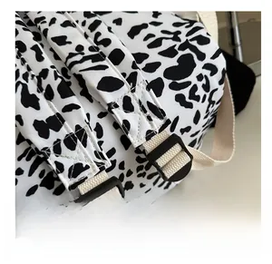 Detail of adjustable black plastic buckles and straps on spotted fabric backpack
