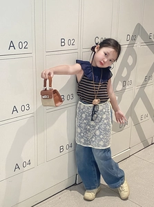 Detailed view of girl's mini canvas handbag paired with vintage denim trousers and vest