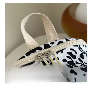 Detail of cow print backpack showing durable webbing handle and dual zippers