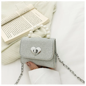 Détail du sac enfant argenté brillant avec poignée en perles et fermoir cœur en métal