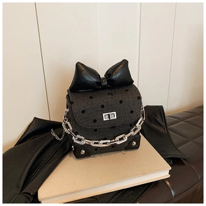 Detailed view of polka dot mini crossbody bag with large bow and silver chain strap