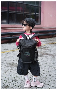 Detail of a black kids backpack with reflective 'STOP' palm print and mesh side pocket
