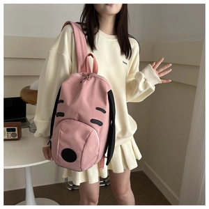 Pink puppy backpack showing main zip pocket and canvas material on female model