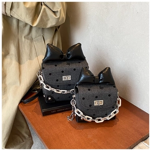 Close-up of grey denim polka dot crossbody bags with oversized black leather bows and chains