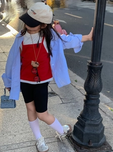 Outdoor street photo of a toddler girl styling a mini blue handbag with sporty outfit