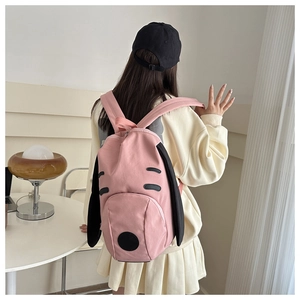Pink dog-themed backpack with long black ears and embroidered cartoon face on model