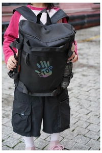 Close-up of kids black backpack featuring a reflective STOP palm print and side mesh pocket
