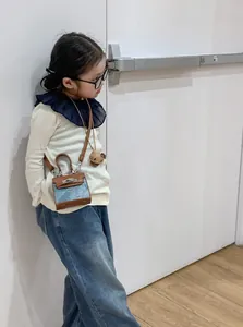 Detail of kids mini denim handbag with leather trim and cartoon plush keychain pendant
