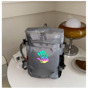 Detail of grey functional kid's backpack featuring holographic STOP palm logo and side mesh pocket