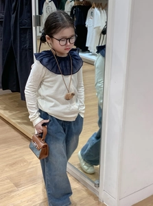 Detail of a mini brown and denim blue color-block handbag held by a child model