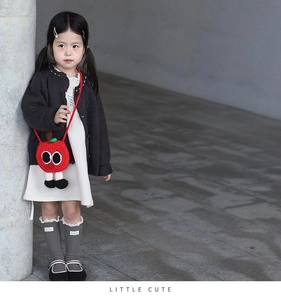Détail du sac bandoulière au crochet pour enfant en forme de pomme avec yeux et petites jambes