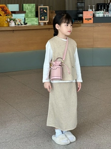 Pink mini bucket bag with drawstring styled on a child in a beige knitted outfit