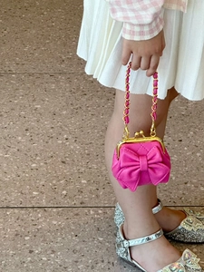 Detail einer pinkfarbenen Kinder-Handtasche mit großer Schleife und Goldkette