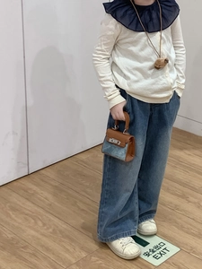 Toddler modeling a mini patchwork handbag with brown leather and blue denim details