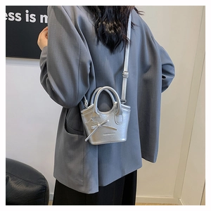 Detail of silver mini tote bag with bow accent, star charm and thin shoulder strap
