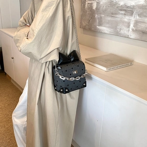 Chic gray polka dot crossbody bag with a large black bow and silver chain strap