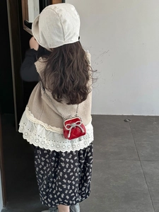 Vista posteriore di una bambina con borsa a tracolla rossa trapuntata e fiocco di strass