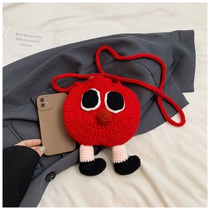 Détail du sac pomme au crochet rouge avec yeux de dessin animé à côté d'un téléphone