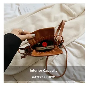 Internal capacity of the brown drawstring bucket bag showing phone and lipstick storage