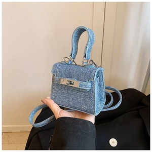 Detail of mini blue denim kids handbag showing metal twist lock and sturdy top handle