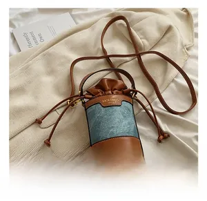 Detail of a mini bucket bag featuring brown leather and blue denim patchwork materials