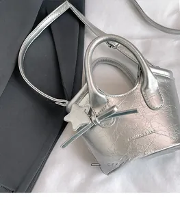 Detail of silver metallic leather mini bag with star charm and cracked texture