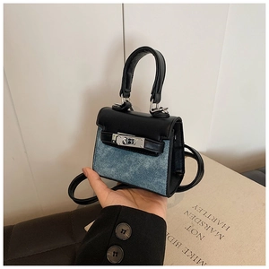 Detail of mini child handbag featuring blue denim and black leather patchwork design