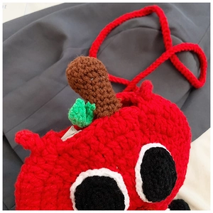 Détail d'un sac pomme fait main au crochet avec de grands yeux et feuilles
