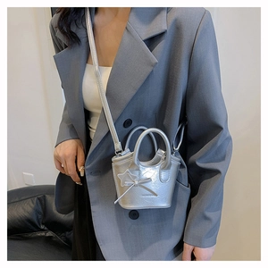 Close-up of silver mini bucket bag with glossy pleated texture and star charm detail