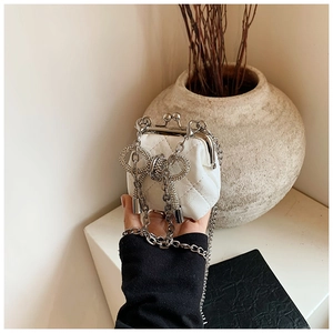 Dettaglio mini borsa trapuntata bianca con fiocco di cristallo e tracolla a catena