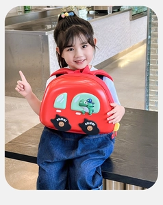 Détail du sac à dos rouge en forme de voiture avec dinosaure et roues à logo pour enfant