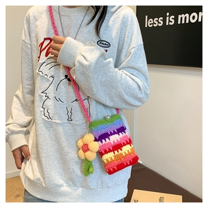 Detail der bunten Häkeltasche mit Sonnenblumen-Anhänger und Perlenverschluss am Modell
