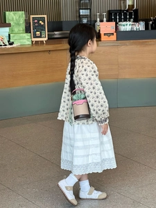 Detail showing the stylish color-block mini bucket bag worn by a child in a cafe