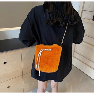 Vista dettagliata di una borsa a secchiello in peluche arancione indossata su nero