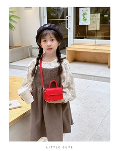 Détail d'un mini sac à bandoulière rouge avec texture tissée sur la tenue d'un enfant