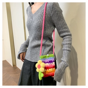 Detail einer handgefertigten Regenbogen-Häkeltasche mit Blumenanhänger und Perlenverschluss